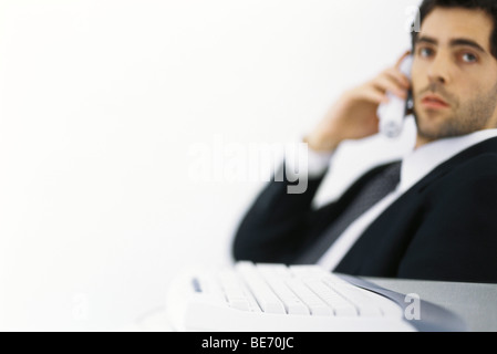 Imprenditore su chiamata telefonica, guardando lontano, tastiera in primo piano Foto Stock