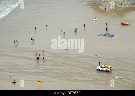 Surfers e bodyboarder e RNLI bagnini sulla spiaggia a Perranporth Cornwall Regno Unito Foto Stock