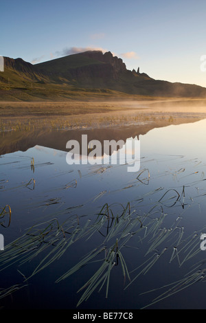 Acqua calma riflettendo il vecchio uomo di Storr rock formazione a distanza, Isola di Skye in Scozia Foto Stock