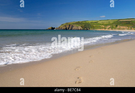 Footprints emergono dalle onde sulla spiaggia sabbiosa Foto Stock