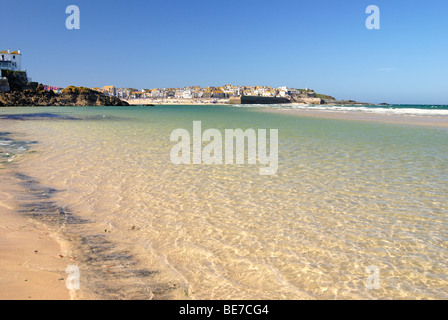 Un mare limpido lambisce una spiaggia di sabbia con St Ives in background Foto Stock
