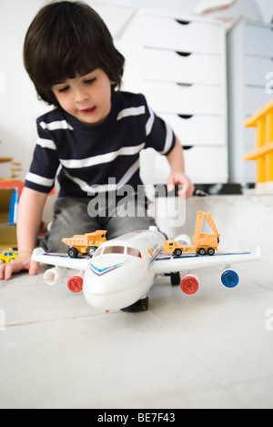 Little Boy giocando con aeroplano giocattolo e camion giocattolo Foto Stock