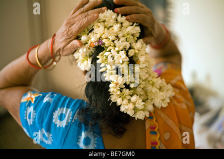 Una donna anziana organizza fiori nei capelli nella sua camera da letto, Janakpuri, New Delhi, India Foto Stock