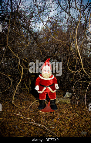 Un anni sessanta era farcito di Santa Claus si erge all'aperto in un groviglio di pennello e overgrowth Foto Stock