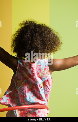 Bambina giocando con il cerchio di plastica, vista posteriore Foto Stock