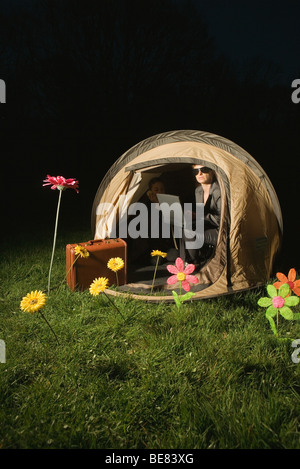 Associa utilizzando laptop in tenda esterna di notte Foto Stock