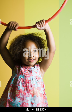 Bambina tenendo premuto cerchio di plastica sopra la sua testa Foto Stock