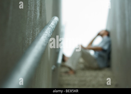 Uomo seduto sui gradini di scale, sfocato Foto Stock