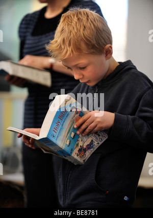 Un giovane ragazzo lettura una bibbia a una scuola domenicale di Regno Unito Foto Stock