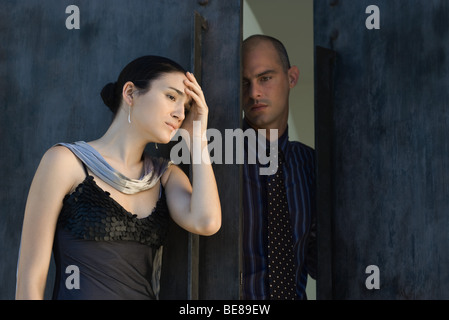 Matura in piedi in porta, donna tenendo la testa, sia cercando di distanza Foto Stock