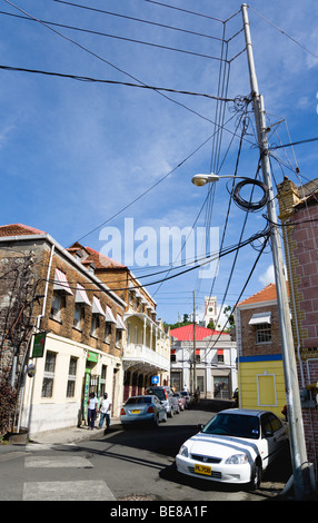 WEST INDIES Caraibi Grenadine Grenada St George la gente a piedi passato auto parcheggiate in strada al di sotto del tettuccio di cavi di alimentazione Foto Stock