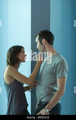 Coppia giovane in piedi faccia a faccia, femmina raggiungendo a toccare Uomo del mento dell Foto Stock