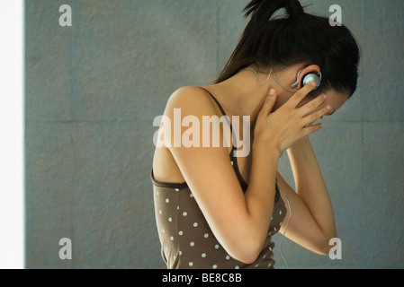 Donna con testa in mani, allontanamento, ascoltare la musica tramite auricolari Foto Stock