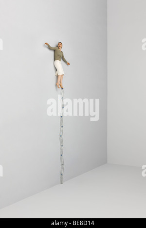 Donna in equilibrio su un piede sulla parte superiore della pila di bottiglie di acqua Foto Stock