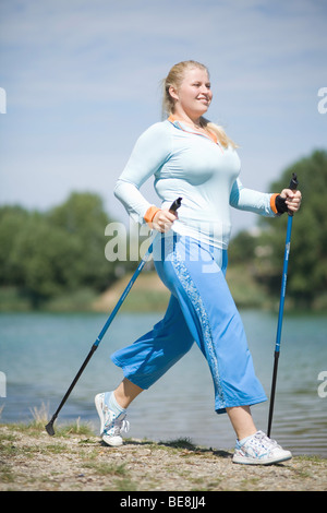 Giovane donna grassa sporting, fare nordic walking. Foto Stock