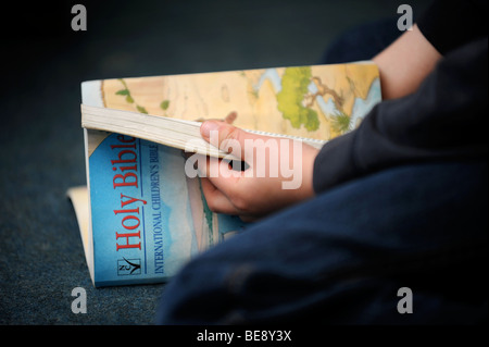 Un giovane ragazzo lettura una bibbia a una scuola domenicale di Regno Unito Foto Stock