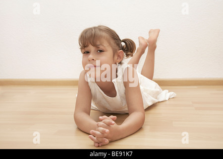 Sei-anno-vecchia ragazza sdraiato sul pavimento Foto Stock