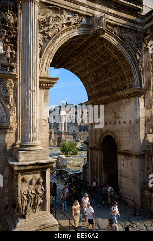 Italia Roma Lazio Forum i turisti a piedi attraverso un arco trionfale di Settimio Severo con il tempio di Castore e Polluce oltre Foto Stock