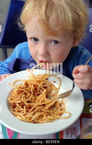 Ragazzo giovane mangiare spaghetti bolognese Foto Stock