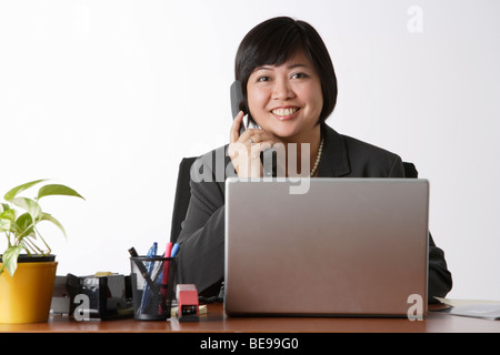 Donna seduta alla scrivania, parlando al telefono Foto Stock