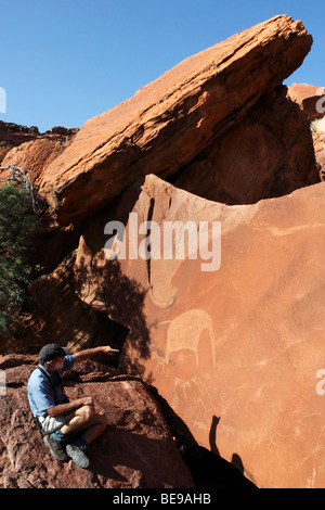 Guardando antiche incisioni dei Boscimani (incisioni rupestri) a Twyfelfontain in Damaraland in Namibia Foto Stock