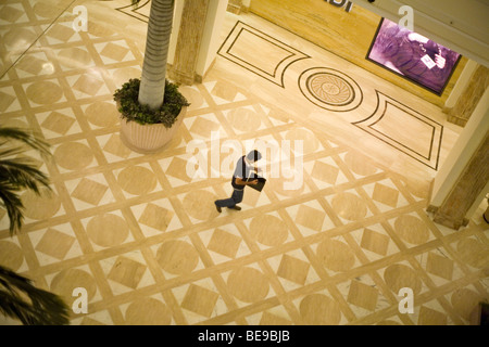 Un uomo guarda nella sua borsa mentre camminando attraverso il DLF Emporio Mall di Vasant Kunj New Delhi, Foto Stock