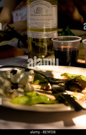 Ancora vita francese di bottiglia di vino, mezza piastra mangiato del cibo delizioso, un bicchiere di vino rosso illuminato dal sole basso su un tavolo Foto Stock