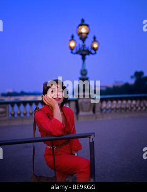 Donna vestita con un tuta da salto rossa sul ponte Alexandre III al crepuscolo, Parigi, Francia, Europa Foto Stock