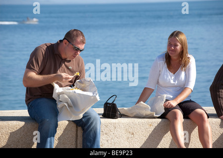 L uomo e la donna a mangiare pesce e patatine sulla parete del mare a Lyme Regis Foto Stock