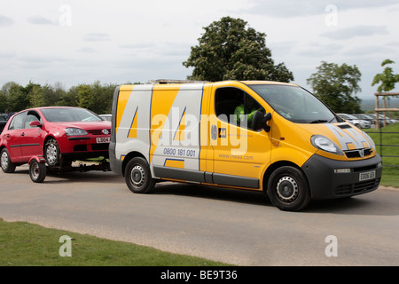 Un recupero di AA van il traino lontano un ripartiti in auto nel Surrey in Inghilterra Foto Stock