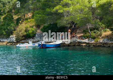 Croazia; Hrvartska; Kroatien, Isola di Hvar bay; 3 giovani uomini riposo dopo la nuotata nella bellissima isola croata bay, 2 piccole imbarcazioni Foto Stock