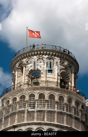 I turisti in cima alla Torre Pendente di Pisa con bandiera rossa di Pisa con Croce Maltese bianca e la scultura di putti Foto Stock