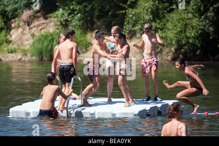 Adolescenti che giocano su un pontone galleggiante nel fiume Lot, Castelmoron, Aquitaine, Francia Foto Stock