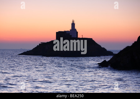 Il sorgere del sole oltre il faro di Mumbles Head, Penisola di Gower vicino a Swansea, West Glamorgan, South Wales, Regno Unito Foto Stock