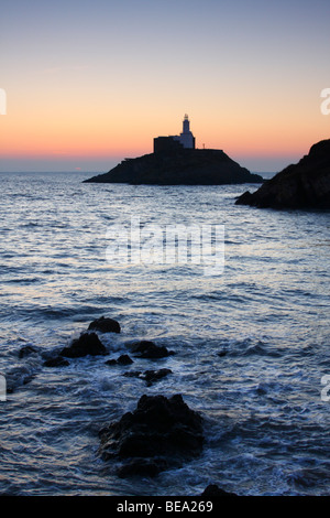 Il sorgere del sole oltre il faro di Mumbles Head, Penisola di Gower vicino a Swansea, West Glamorgan, South Wales, Regno Unito Foto Stock