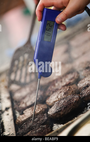 Usando un termometro digitale per controllare che gli hamburger sono cotti bene a Abergavenny food festival, Monmouthshire Wales UK Foto Stock