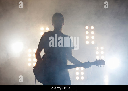 Un musicista rock suonando una chitarra su un palco Foto Stock