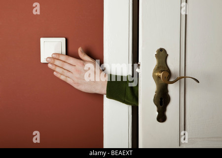 Una mano di spegnere un interruttore della luce Foto Stock