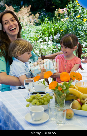 Una sorella dando il suo fratello un regalo di compleanno Foto Stock