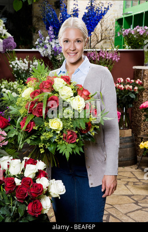 Donna che mantiene un bouquet di rose in un fioristi Foto Stock