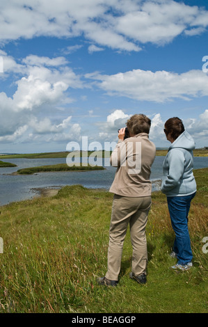 dh Women birdwatchers HARRAY ORKNEY usando binocolo guardando sopra Harray Loch birdwatchers scozia birdwatcher Foto Stock