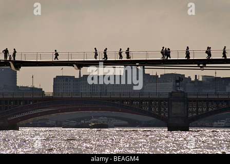 Stagliano pendolari sul Millennium ponte che attraversa il fiume Tamigi. Londra, Inghilterra Foto Stock