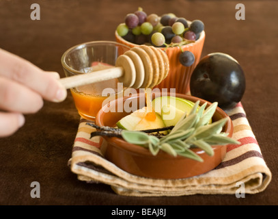 Il miele gocciolare su un verde fette di mela e altri frutti Foto Stock