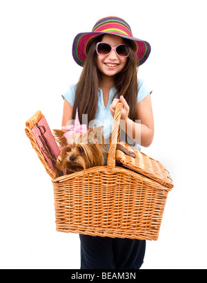 Ragazza che indossa un strow cappello e occhiali da sole rosa, tenendo un cestino da pic nic con Yorkshire terrier cane Foto Stock