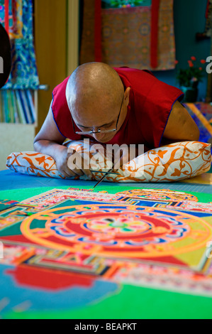 Monaco tibetano VenoDhondup Tsering opere attentamente su un coloratissimo Mandala di sabbia in Ruidoso, Nuovo Messico. Foto Stock