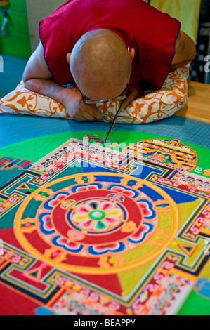 Monaco tibetano VenoDhondup Tsering opere attentamente su un coloratissimo Mandala di sabbia in Ruidoso, Nuovo Messico. Foto Stock