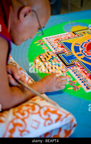 Monaco tibetano VenoDhondup Tsering opere attentamente su un coloratissimo Mandala di sabbia in Ruidoso, Nuovo Messico. Foto Stock