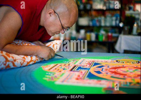 Monaco tibetano VenoDhondup Tsering opere attentamente su un coloratissimo Mandala di sabbia in Ruidoso, Nuovo Messico. Foto Stock