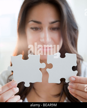 Donna ispanica tenendo due pezzi di un puzzle Foto Stock