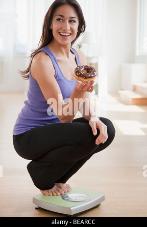 Donna ispanica holding donut e accovacciato su scala Foto Stock